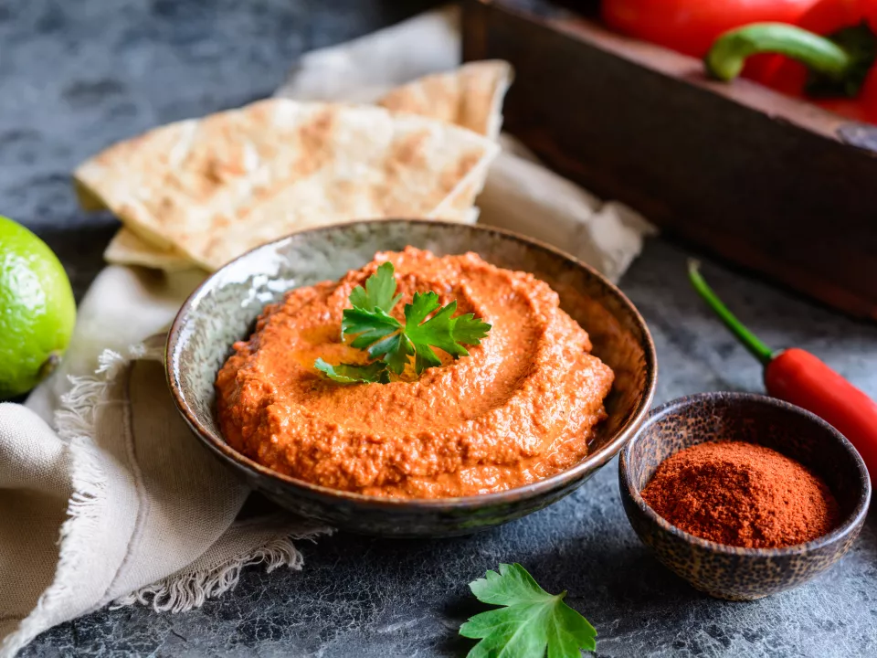 Muhammara in een kommtje afgewerkt met een blaadje platte peterselie Muhammara in een kommtje afgewerkt met een blaadje platte peterselie